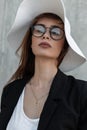 Beautiful pretty young woman with beauty lips in elegant glasses in sexy top in fashion black blazer and summer straw hat near Royalty Free Stock Photo