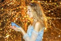 Beautiful princess in blue long dress on the luminous yellow tree background with blue crystal shoe in her hand. Art Royalty Free Stock Photo