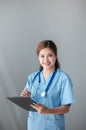 Beautiful and professional Asian female doctor in uniform with stethoscope open palm, smiling, looking at camera Royalty Free Stock Photo