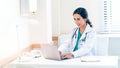 Beautiful and professional female doctor using laptop computer, working at her desk in the doctor's office Royalty Free Stock Photo