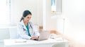 Beautiful and professional female doctor using laptop computer, working at her desk in the doctor's office Royalty Free Stock Photo