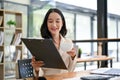 A beautiful Asian businesswoman reviewing a business report and sipping her coffee at her desk