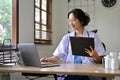 Beautiful Asian female doctor using laptop computer, working at her desk in the doctor`s office Royalty Free Stock Photo