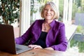 A beautiful professional senior woman working on her laptop from home