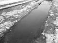 Beautiful puddles with ice crust, snow and reflection in winter or spring