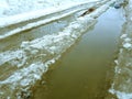 Beautiful puddles with ice crust, snow and reflection in winter or spring