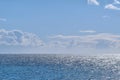 Beautiful puffy clouds in a blue sky rolling over a calm blue sea and ocean in summer. Gorgeous scenic view of the beach