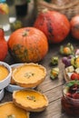 Beautiful pumpkin pies lying next to pumpkins on a wooden table