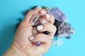 Beautiful purple amethyst crystals in rock crystal in hand. Semi-precious stones in a female hand against the background of other Royalty Free Stock Photo