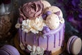 Beautiful purple cake decoraited of fresh flowers, macaroons and meringue.