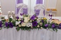 Beautiful purple and creamy flowers on table of newlyweds at wedding reception in restaurant, free space. Wedding table decorated