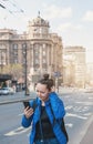 Beautiful puzzled tourist woman with mobile phone and backpack get lost near road in the Belgrade city, Serbia Royalty Free Stock Photo