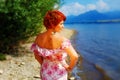 Beautiful radiant girl with red hair and colorful sommer dress beside a lake.