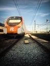 Beautiful railway station with modern orange commuter train at sunny day in Vilanova, Spain. Railroad with vintage toning