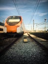 Beautiful railway station with modern orange commuter train at sunny day in Vilanova, Spain. Railroad with vintage toning