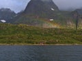 Rainbow above traditional wooden house with red facade on shore of Raftsundet strait on AustvÃÂ¥gÃÂ¸ya island, Lofoten, Norway. Royalty Free Stock Photo