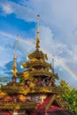 Beautiful rainbow over the ancient wooden temple. Shan-Thai buddhism temple. Tropical trees are in bloom backgrounds. Thai-Myanmar