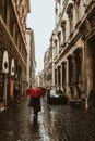 Beautiful rainy street of Rome with people under umbrella silhouettes for lifestyle design. Summer season. Dark and