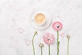 Beautiful ranunculus flowers and cup of coffee on white table from above. Breakfast in pastel color. Flat lay style.