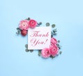 Beautiful ranunculus flowers and greeting card with text Thank You on light blue background, flat lay Royalty Free Stock Photo