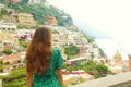 Beautiful rear view of a romantic sweet woman in green dress looking at Positano village from a terrace, Amalfi Coast, Italy