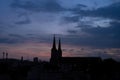 Beautiful red and blue sunrise sky with clouds over black silhouette of city with tower of church on horizon. Silhouette of the Royalty Free Stock Photo