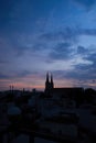 Beautiful red and blue sunrise sky with clouds over black silhouette of city with tower of church on horizon. Silhouette of the Royalty Free Stock Photo