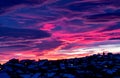 Beautiful red-blue sunset over the city with dark clouds. Dark silhouette of a winter city with beautiful dawn. Artistically