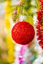 Beautiful red Christmas ball and shining tinsel hanging on branch of tree. Selective focus in foreground, colorful Royalty Free Stock Photo