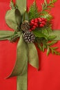 Beautiful red and green Christmas gift present with fabric ribbon bow and botanical decorations. Vertical background image. Royalty Free Stock Photo