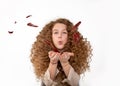 Beautiful redhaired curly long hair girl blowing feathers from hands. The concept of gentle care for skin, hair, softness and