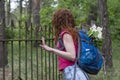 Beautiful red hair woman with backpack looking over the fence Royalty Free Stock Photo