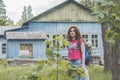 Beautiful red hair woman tourist with backpack near the house in the forest Royalty Free Stock Photo