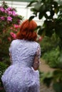 Red-haired girl in arranger where azalea blooms in a colorful flying dress Royalty Free Stock Photo