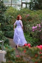 Red-haired girl in arranger where azalea blooms in a colorful flying dress Royalty Free Stock Photo