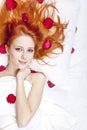 Beautiful red-haired girl in bed with rose petal. Royalty Free Stock Photo
