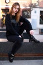 A beautiful red-haired girl, in black clothes, sits with a cup of coffee Royalty Free Stock Photo