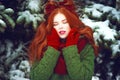 Beautiful red haired girl with creative hairstyle posing with closed eyes in front of snow covered firtrees Royalty Free Stock Photo