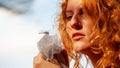 Beautiful red-haired girl is fascinated by the dragonfly, which has landed on the cloth in your hands, copy space