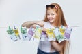 Beautiful red-haired girl hangs euro banknotes on a rope