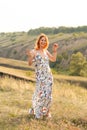 Beautiful red-haired girl is having fun and dancing in a field at sunset Royalty Free Stock Photo