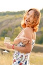 Beautiful red-haired girl is having fun and dancing in a field at sunset Royalty Free Stock Photo