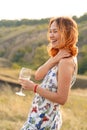 Beautiful red-haired girl is having fun and dancing in a field at sunset Royalty Free Stock Photo