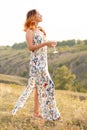 Beautiful red-haired girl is having fun and dancing in a field at sunset Royalty Free Stock Photo