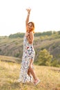 Beautiful red-haired girl is having fun and dancing in a field at sunset Royalty Free Stock Photo