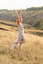 Beautiful red-haired girl is having fun and dancing in a field at sunset Royalty Free Stock Photo