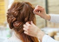 Beautiful, red-haired girl with long hair, hairdresser weaves a French braid, in a beauty salo Royalty Free Stock Photo