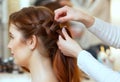 Beautiful, red-haired girl with long hair, hairdresser weaves a French braid, in a beauty salon Royalty Free Stock Photo