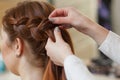 Beautiful, red-haired girl with long hair, hairdresser weaves a French braid, in a beauty salon. Royalty Free Stock Photo