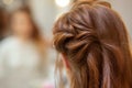 Beautiful, red-haired girl with long hair, hairdresser weaves a French braid, in a beauty salon. Royalty Free Stock Photo